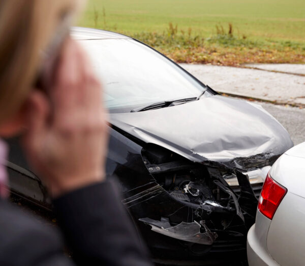 woman on phone overlooking a road traffic collision