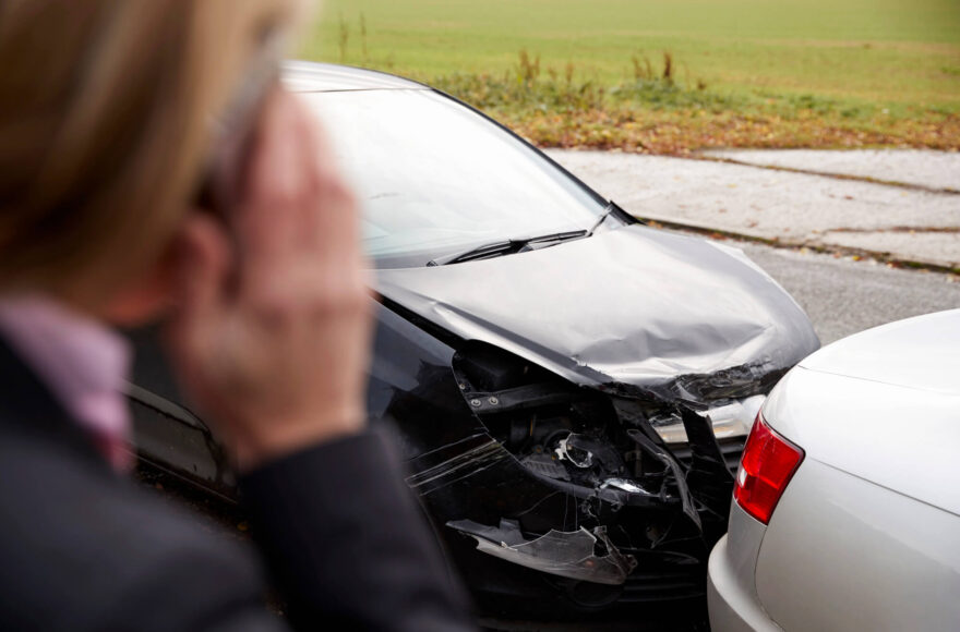 woman on phone overlooking a road traffic collision